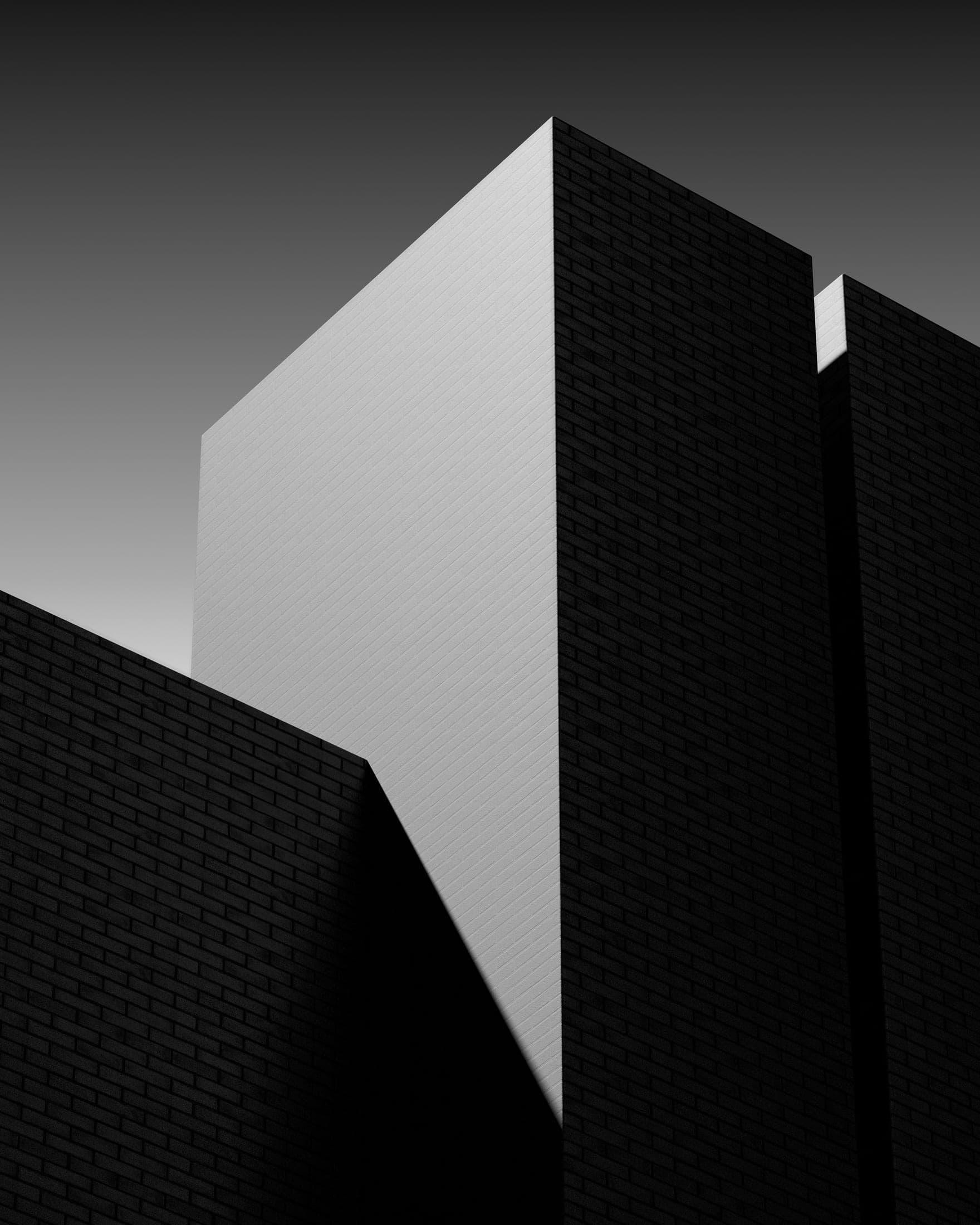 Volume blanc se détachant d’une façade de brique sombre.